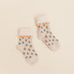 Close-up of Kennedy socks in Spice by Shop Little Millers, showing a cream-colored knit fabric with dainty floral accents and fine heart-style trim, soft ribbed cuff, and flexible stretch designed to keep baby and children’s feet comfortable while playing or dressing up.